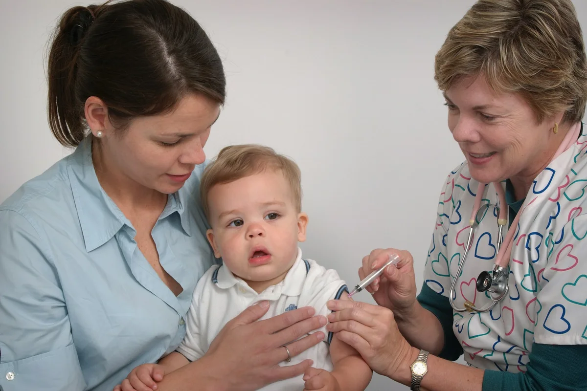 Bebê no colo da mãe recebendo vacina durante atendimento pediátrico